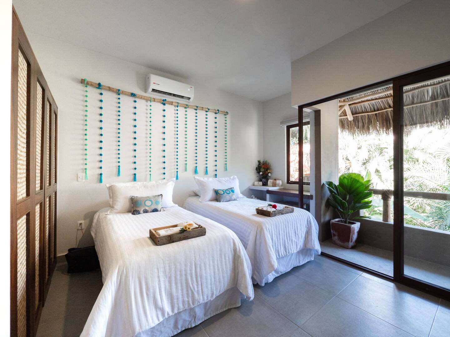 Upstairs twin bedroom at Villa Vargas Sayulita with two single beds, a beaded wall hanging, air conditioning and sliding doors to the terrace
