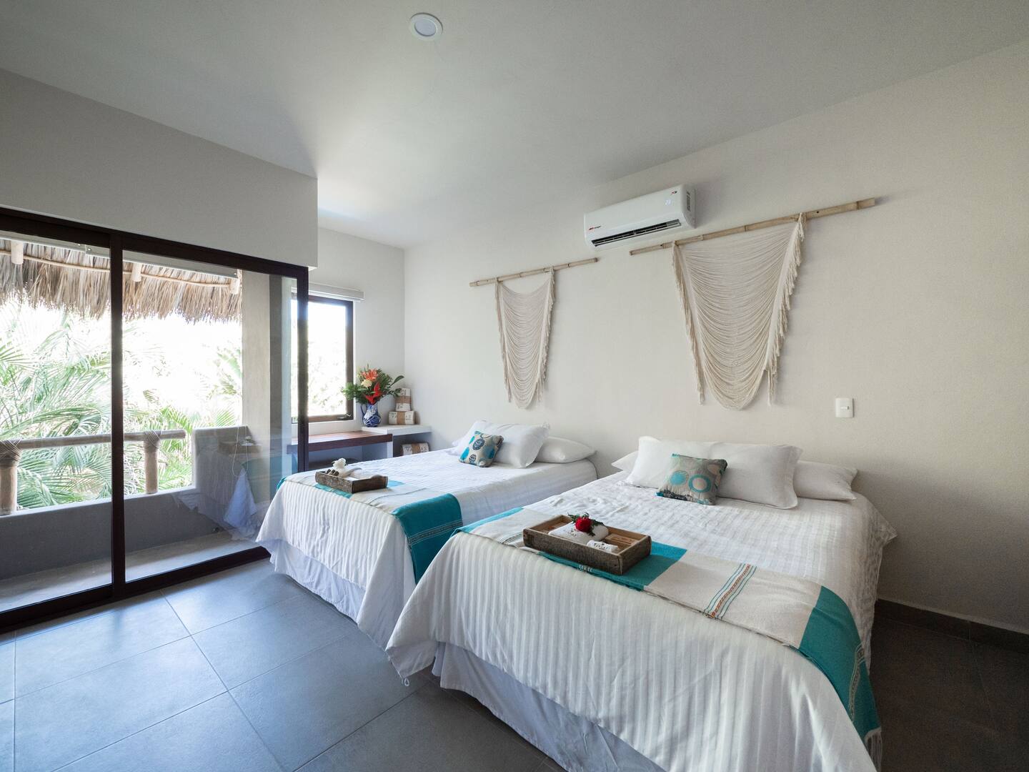 Upstairs bedroom at Villa Vargas Sayulita with two queen beds, macramé wall hangings, air conditioning and sliding doors to the balcony