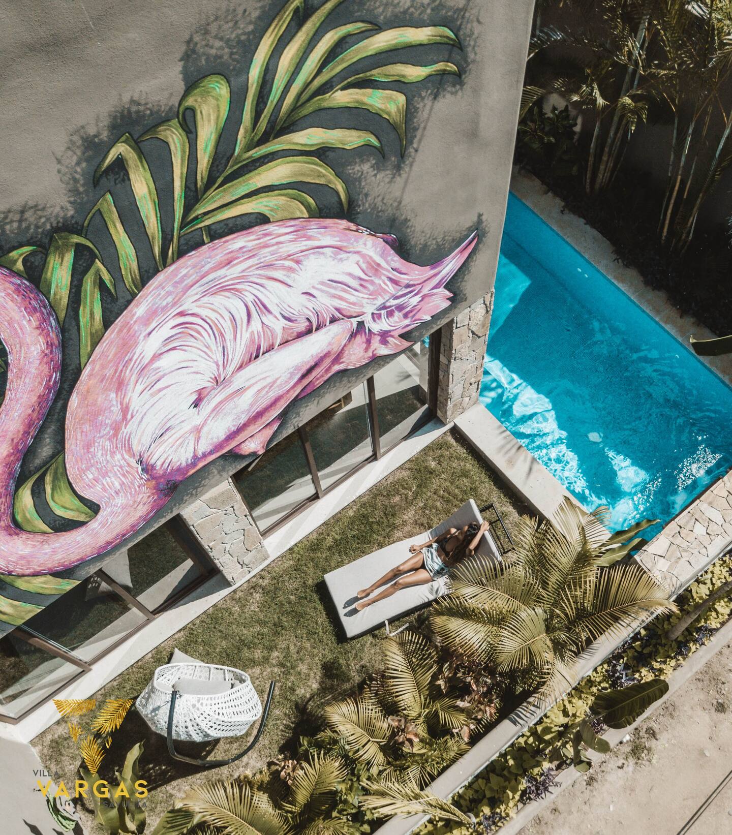 Looking down on the garden terrace and pool at Villa Vargas Sayulita from above, with sun loungers and the painted flamingo wall