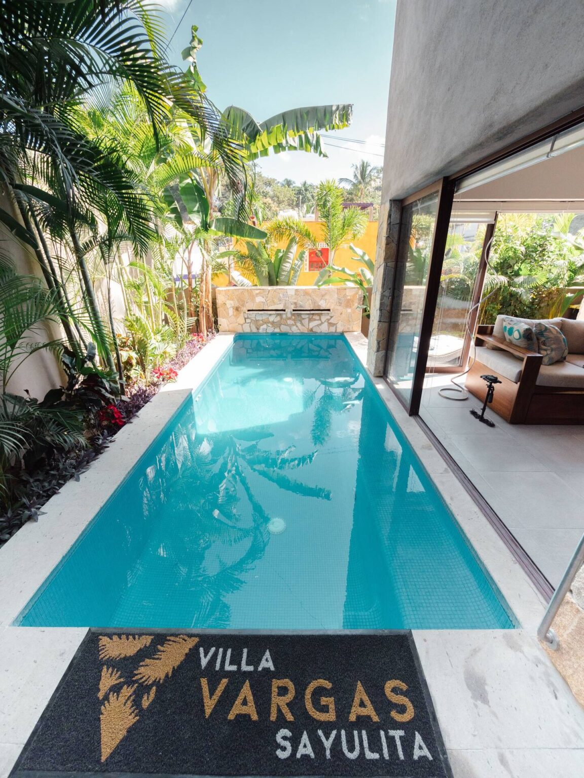 The full length of the private pool at Villa Vargas Sayulita seen from the upper level, bordered by tropical planting and the terrace