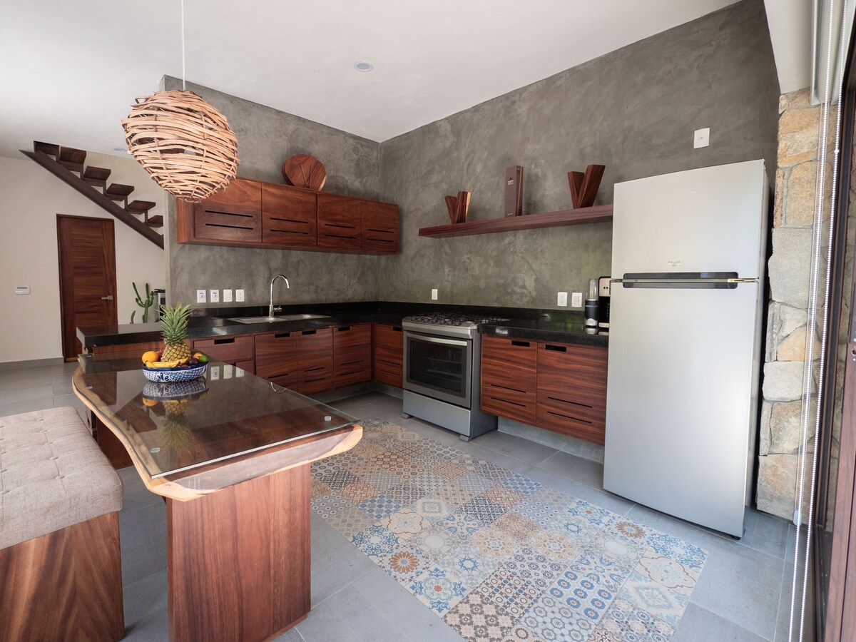 Modern kitchen at Villa Vargas Sayulita with wood cabinetry, waterfall island, and stainless steel appliances