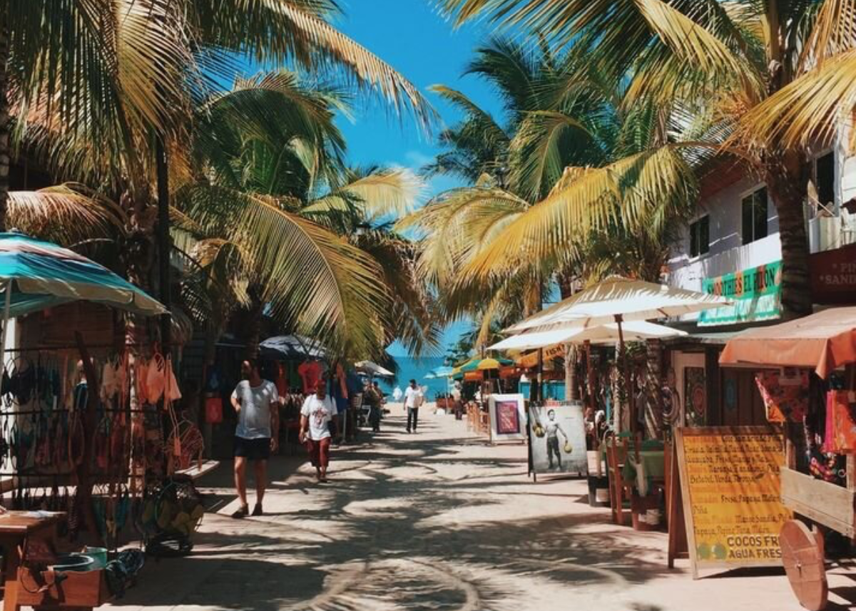 A palm-lined street in Sayulita with shops and umbrellas leading down toward the beach