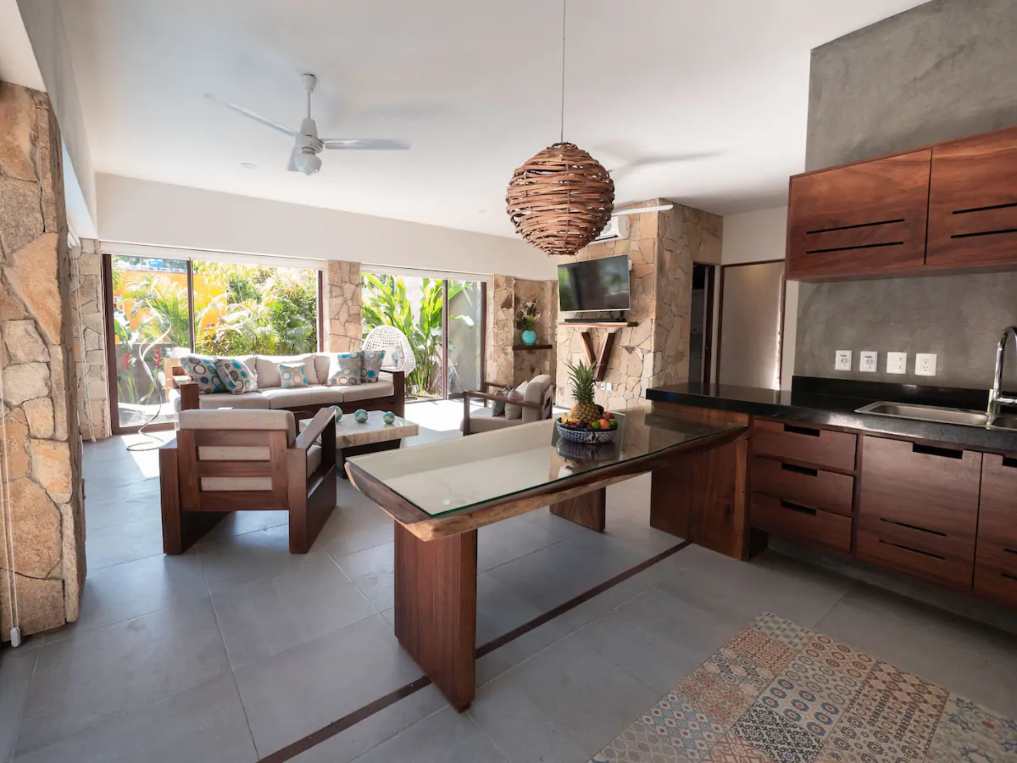 The open ground floor at Villa Vargas Sayulita — kitchen, dining table and living room running together, with sliding doors onto the pool