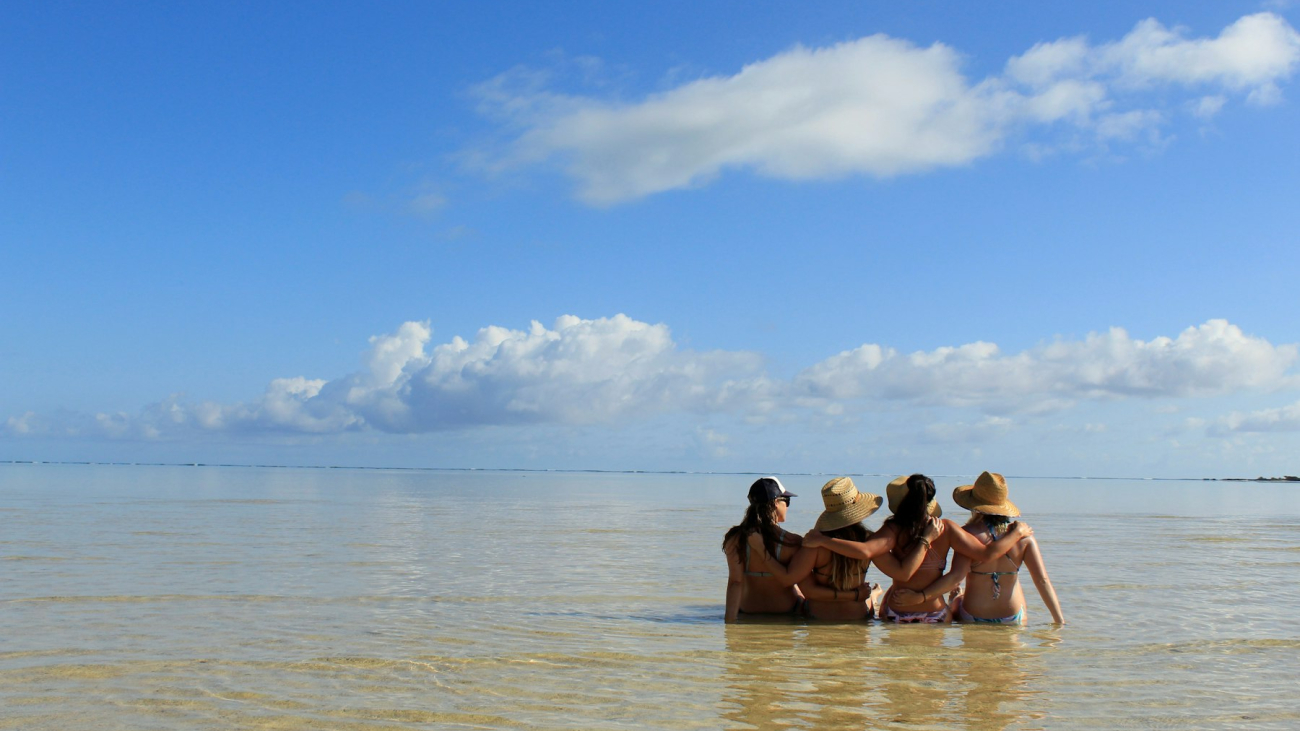 Four friends sitting in the ocean shallows, a bachelorette or girls trip to Sayulita