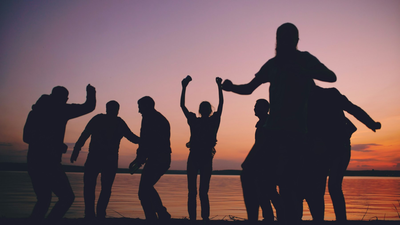 Silhouettes of a group of friends celebrating at sunset by the water, a group trip to Sayulita