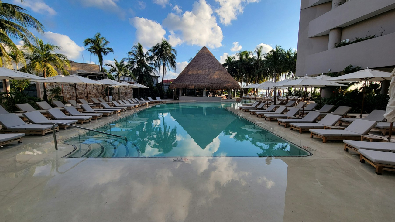 Large hotel swimming pool with lounge chairs and umbrellas, villa vs hotel vs Airbnb in Sayulita