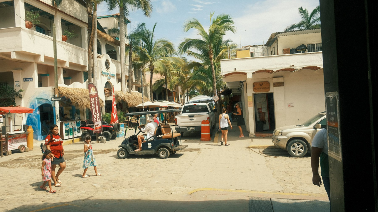 People walking down a Sayulita street next to parked cars — is Sayulita safe