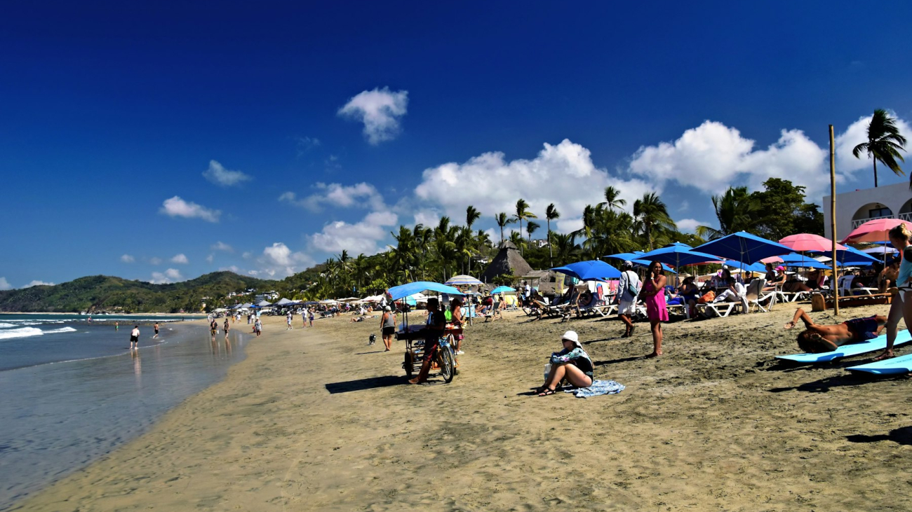People relaxing on a sunny Sayulita beach with umbrellas — best time to visit Sayulita