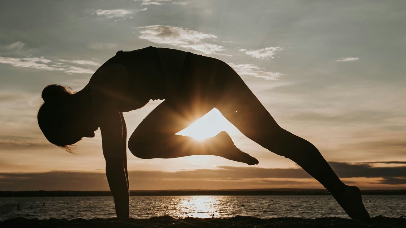 Woman in a yoga pose in front of the setting sun, yoga in Sayulita