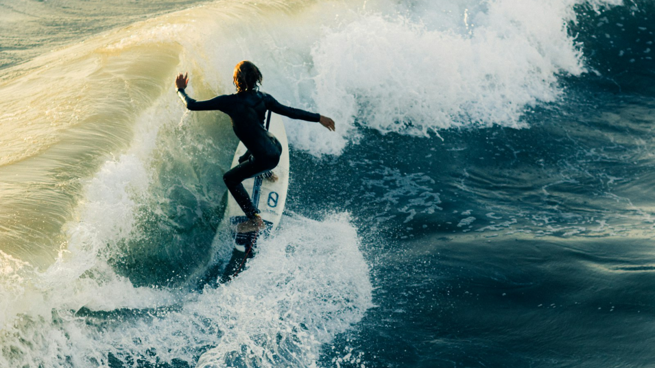A surfer riding a wave during the day, representing the surf breaks around Sayulita